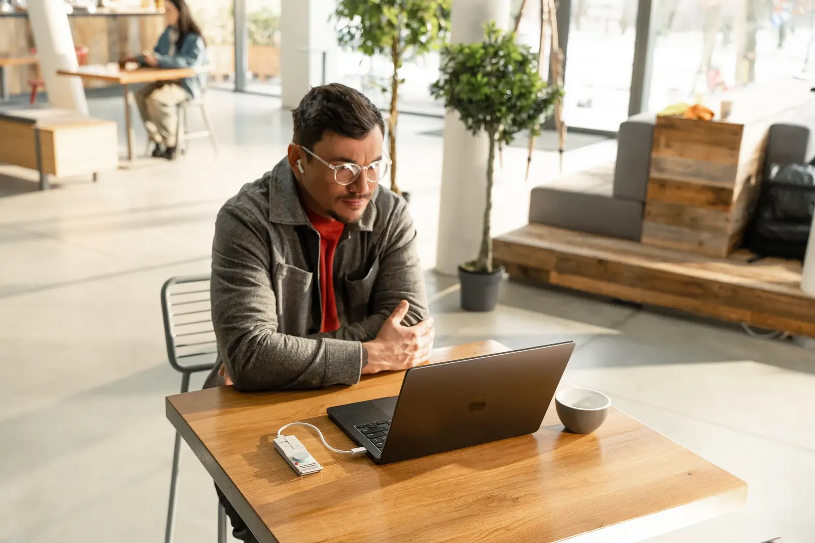 HiDock P1 capturing a remote meeting from a laptop in a cafe
